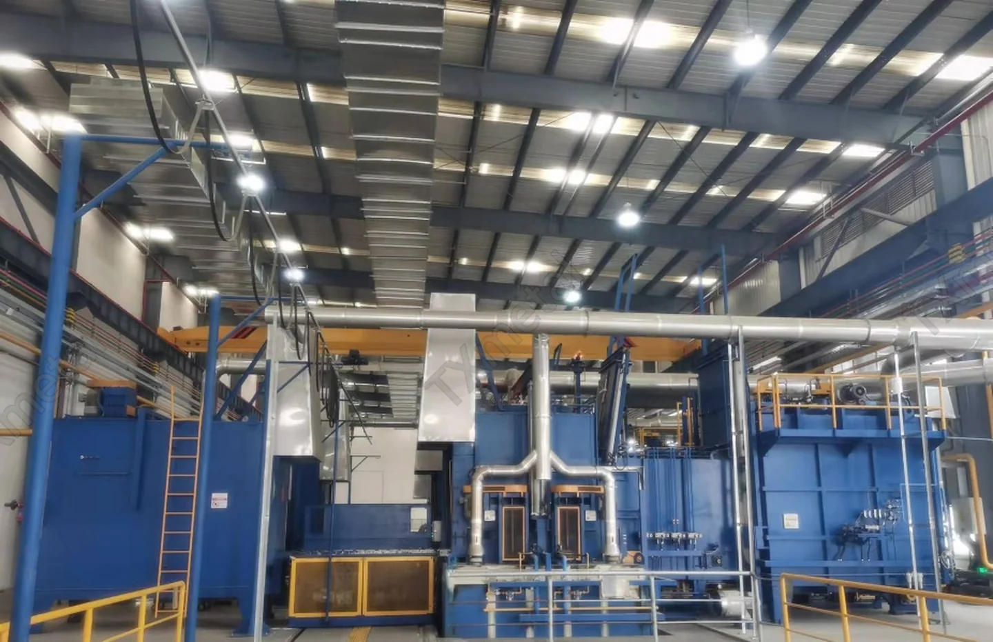 Industrial heat treatment line for processing gray iron, ductile iron, and ADI castings in a foundry.